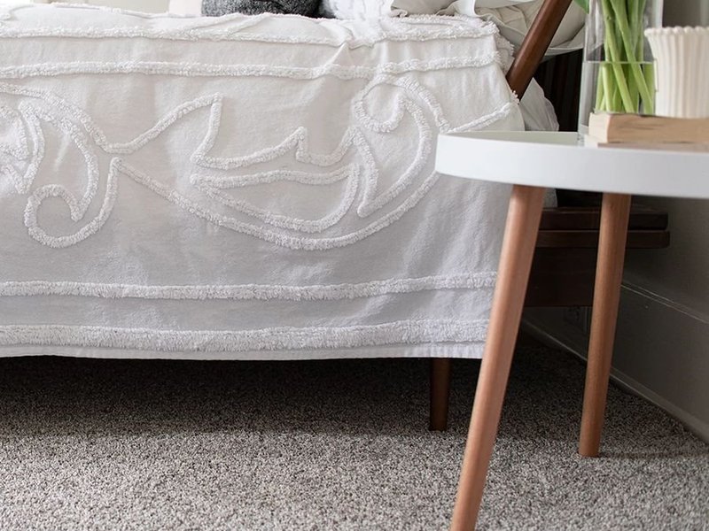 Bedroom with gray carpet and a white end table with a houseplant on it - Floor Fashions of Virginia in the Charlottesville, VA area