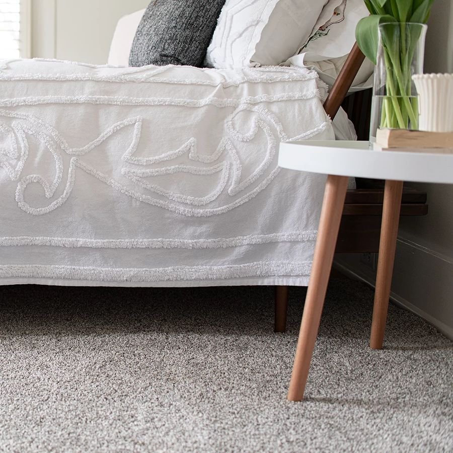 Bedroom with gray carpet and a white end table with a houseplant on it - Floor Fashions of Virginia in the Charlottesville, VA area